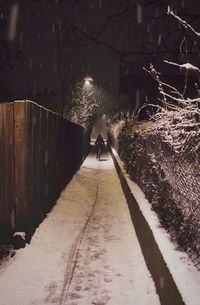 Man walking on illuminated walkway at night