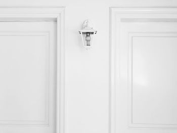 A lonely white lamp on a white background between two doors