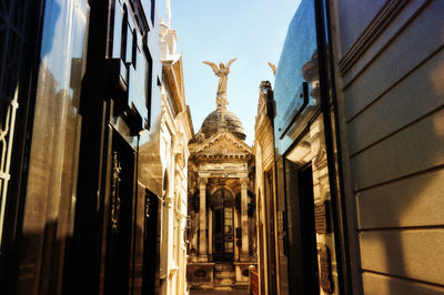 Low angle view of statue amidst buildings against sky