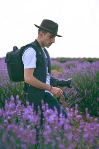 Man with camera walking amidst blooming flowers