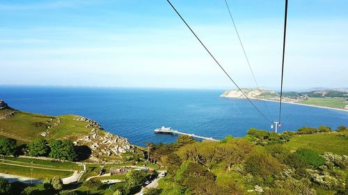 Overhead cable cars over coastline against sky