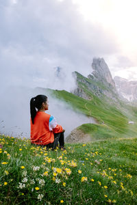 Rear view of woman on grass against sky