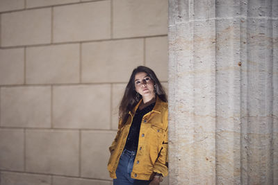 Portrait of young woman leaning against pillar 