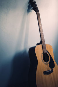 Close-up of guitar against wall at home
