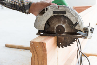 Close-up of man working on wood with circular saw