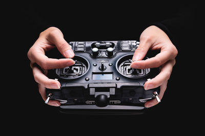 Close-up of hand holding camera against black background