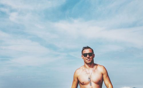 Portrait of young man wearing sunglasses standing at beach