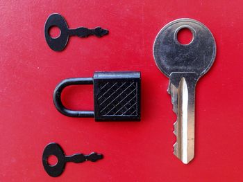 High angle view of keys and padlock against red background