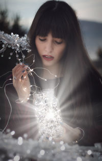 Portrait of woman with illuminated christmas lights