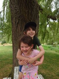 Brother and sister playing in park next to willow tree