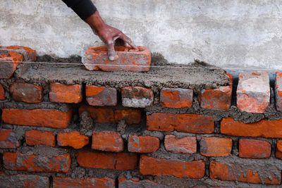 Close-up of man holding brick wall