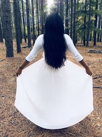 Rear view of woman against tree in forest