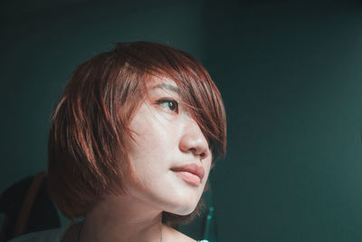 Close-up portrait of young woman against gray background