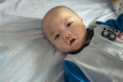 Portrait of cute baby lying on bed