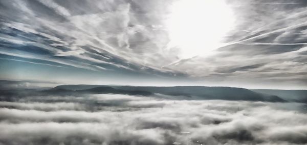 Low angle view of sunlight streaming through clouds