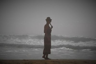 Full length of man standing on beach against sky