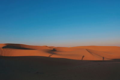 Scenic view of desert against clear blue sky