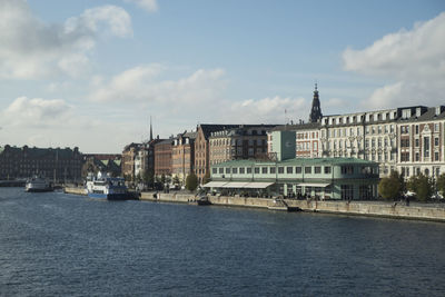 Buildings by river against sky in city