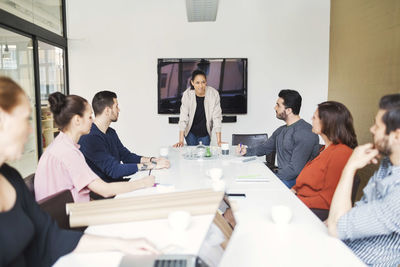 Young businesswoman giving presentation to colleagues in conference room