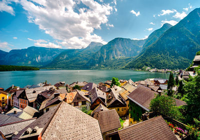 Panoramic view of village on lake and mountains against sky