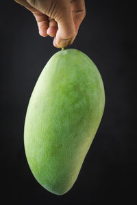 Close-up of hand holding apple against black background