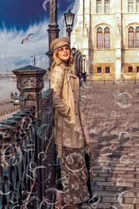 Portrait of young woman standing against building in city