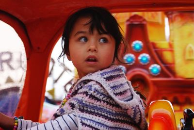 Close-up of cute girl looking away while sitting in ride