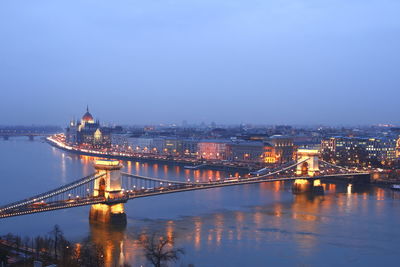 Illuminated bridge over river against sky in city at night