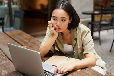 Young woman using laptop at cafe