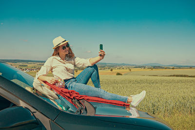 Side view of man sitting on car