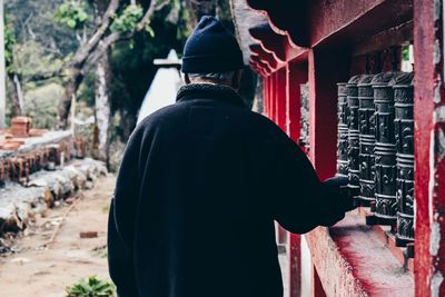 Rear view of man spinning prayer wheels at enchey monastery