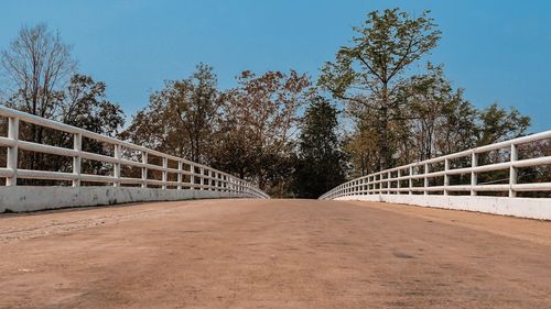 Footpath by footbridge against sky