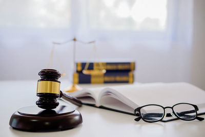Close-up of book with eyeglasses and gavel on table in office