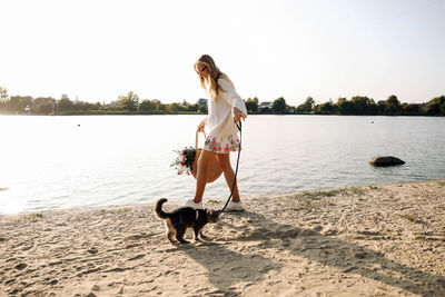 Rear view of young woman with dog on beach
