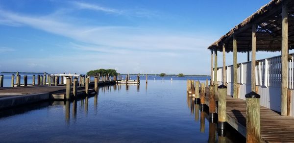 Wooden posts on pier by sea against sky