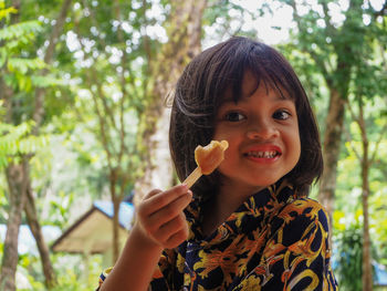 Smiling girl holding ice cream outdoors