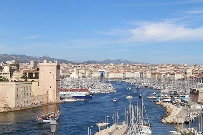 Boats on sea at vieux port by buildings against sky