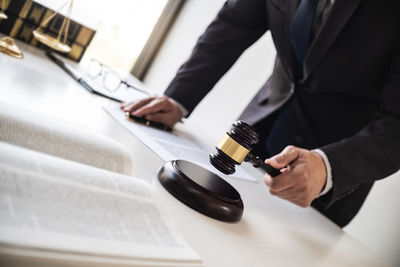 Midsection of man reading book on table