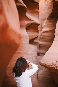 Rear view of woman standing amidst rock formation