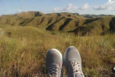 Shoes on field against sky