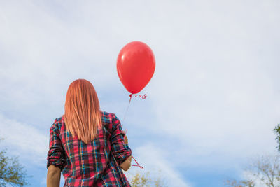 Low angle view of woman on balloons against sky