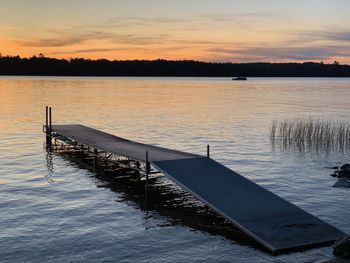 Pier on lake against sky during sunset