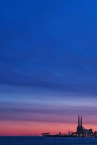 Sea and buildings against sky during sunset