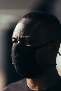 Closeup portrait of african american man wearing a black mask. he is looking away with serious expression