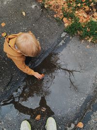A high-angle view of a boy sitting near a puddle
