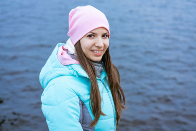 Happy tourist woman on the bank of the river in autumn in warm clothes.