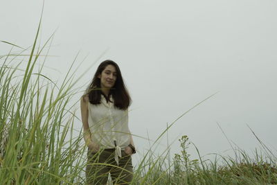 Portrait of young woman standing on land against sky