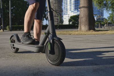 Low section of man riding push scooter on street