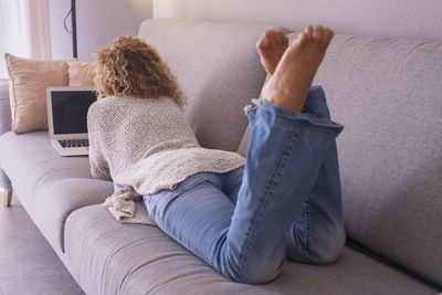 Midsection of woman using mobile phone while sitting on sofa at home