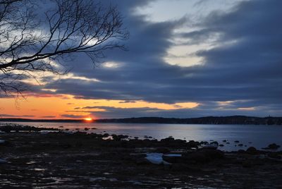 Scenic view of sea against cloudy sky at sunset